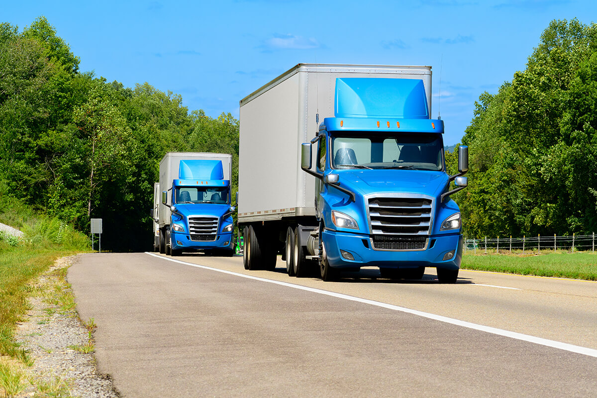 Two Blue Semis Travel Down An Interstate Highway (2)